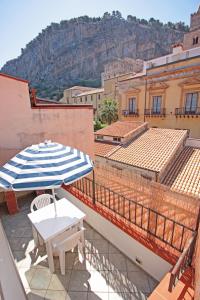 een balkon met een parasol en een tafel en stoelen bij Terrazza Cathedral con vista by Wonderful Italy in Cefalù