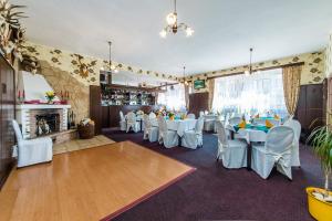 a restaurant with white tables and chairs and a fireplace at Hotel & Motorest V Údolí Zlatého potoka in Blšany