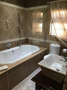 een badkamer met een bad en een wastafel bij Le Cozmo Guesthouse in Johannesburg