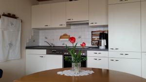 wazon z czerwonymi kwiatami na stole w kuchni w obiekcie Ferienwohnung Sonja w mieście Edeldorf