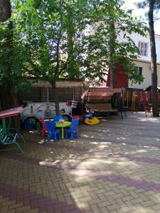 ゲレンジークにあるГостевой дом Асиятの木の下にカラフルなテーブルと椅子が備わるパティオ