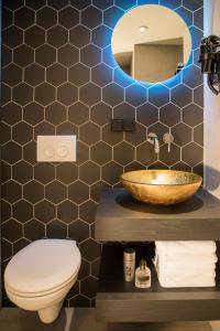 een badkamer met een wastafel, een toilet en een spiegel bij "Buitendijks Genieten" in Dreumel