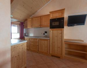 a kitchen with wooden cabinets and a tv on the wall at La Grolla Rooms & Apartments in Livigno