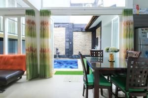 a dining room with a table and chairs and a pool at Donata House in Jimbaran