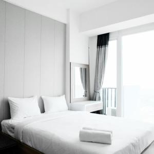 a white bedroom with a white bed with a window at Homey Studio Room Tree Park City BSD Apartment near BSD City By Travelio in Tangerang