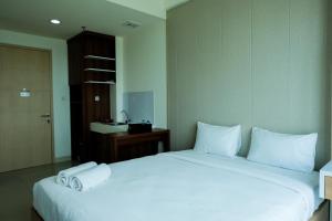 a bedroom with a large white bed with towels on it at Homey Studio Room Tree Park City BSD Apartment near BSD City By Travelio in Tangerang +9 photos
