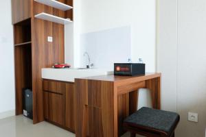 a bathroom with a counter with a sink and a stool at Homey Studio Room Tree Park City BSD Apartment near BSD City By Travelio in Tangerang