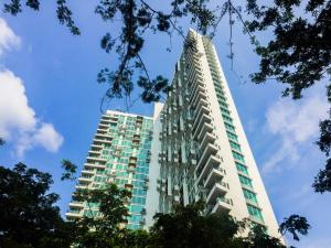 a tall white building with trees in the foreground at Homey Studio Room Tree Park City BSD Apartment near BSD City By Travelio in Tangerang