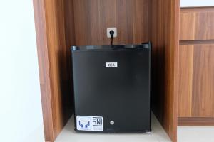 a small black refrigerator in a wooden cabinet at Homey Studio Room Tree Park City BSD Apartment near BSD City By Travelio in Tangerang