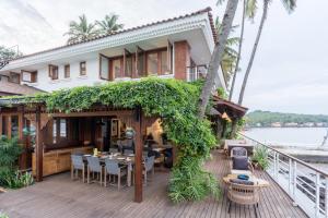 a house with a deck with a table and chairs at StayVista at Villa Kinara The Luxury Collection in Old Goa