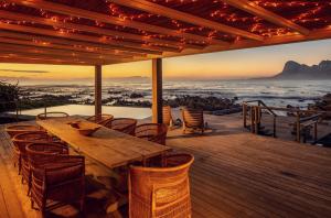 a wooden table on a deck with a view of the ocean at Pringle Bay Villa by Raw Africa Collection in Pringle Bay