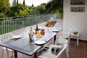 a wooden table with white chairs and wine bottles on a balcony at The Yellow House in Mataelpino