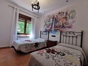 a bedroom with two beds and a painting on the wall at Casa Rural Ruiz Hernando in Villanueva del Arzobispo