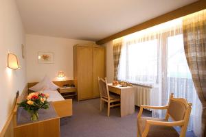 ein Hotelzimmer mit einem Bett, einem Schreibtisch und einem Tisch in der Unterkunft Kurhotel Dornröschen in Bad Wörishofen