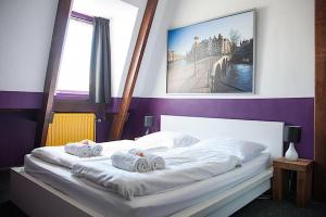 una camera da letto con un letto bianco e asciugamani di The Flying Pig Downtown ad Amsterdam Altre 24 foto