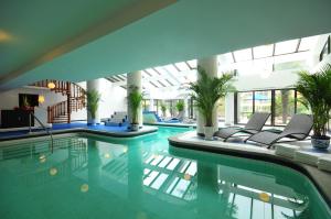 a swimming pool with chairs and plants in a building at Jianguo Hotel Xi'an in Xi'an