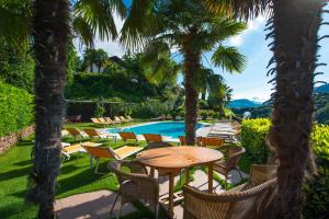 eine Terrasse mit Tisch und Stühlen und ein Pool in der Unterkunft Hotel Weinberg in Appiano sulla Strada del Vino