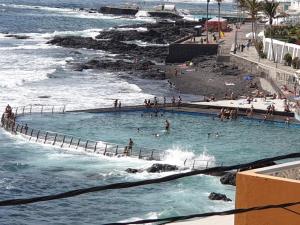 Leute schwimmen in einem Pool neben dem Meer in der Unterkunft Primera linea del mar in Punta del Hidalgo