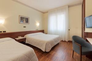 una camera d'albergo con due letti e una televisione di Palace Hotel a Civitanova Marche
