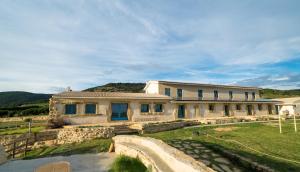 Is Perdas Rural Retreat & Spa في Gergei: منزل أبيض كبير مع ساحة عشبية