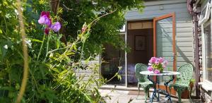 een patio met een tafel, stoelen en bloemen bij The Old Forge in Totnes