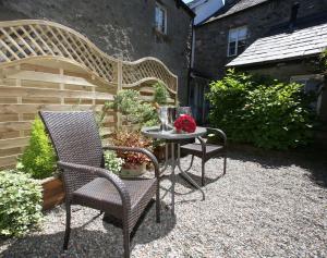 a patio with two chairs and a table with flowers at No 2 in Kirkby Lonsdale