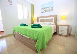 een slaapkamer met een bed met een groene deken erop bij Apartment AMARA in Estepona