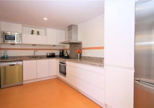 una cocina con armarios blancos y electrodomésticos de acero inoxidable en Apartment AMARA, en Estepona