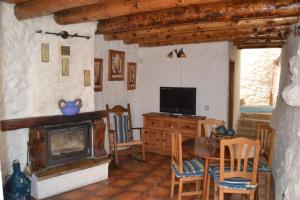 un salon avec une cheminée, une table et une télévision dans l'établissement Casas Rurales La Tejeruela, à Yeste