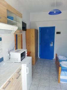 eine Küche mit einer Mikrowelle und einer blauen Tür in der Unterkunft Vangelis Studios in Skala Potamias