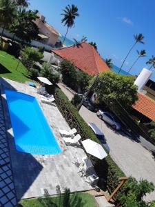 una piscina con sedie e ombrelloni accanto a una casa di Condomínio Merepe Residence Duplex a Porto De Galinhas