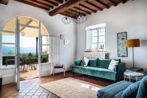 a living room with a green couch and an open door at Appartamento con magnifica vista e piscina in Lucca
