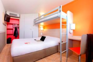 a bedroom with a bunk bed with a laptop on it at Premiere Classe Toulouse Sesquières in Toulouse