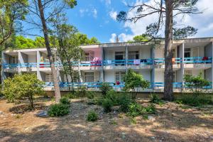 a large white building with trees in the foreground at Hotel Alem in Baška Voda