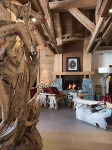 a living room with a large tree trunk and a fireplace at CGH Résidences & Spas Le Village De Lessy in Le Grand-Bornand