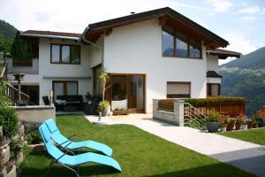a house with a lawn and a blue chair at Ferienwohnung Christina Gundolf in Wenns
