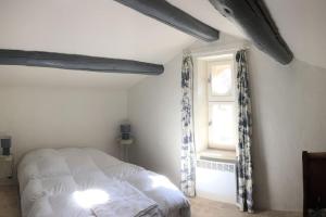 1 dormitorio con cama blanca y ventana en La Magnanerie, en Bonnieux