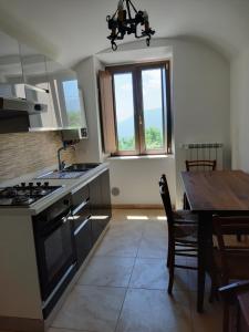 una cucina con tavolo e piano cottura forno superiore di Casa Iacobucci a Fagnano Alto