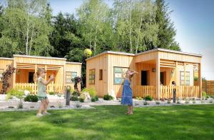 dos chicas jugando con una pelota delante de una casa en Honey Paradise glamping resort, en Dobova