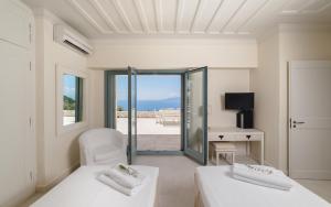 a white room with two beds and a view of the ocean at Urania Luxury Villas in Vasiliki