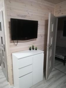 a living room with a tv and a white dresser at Bajkowe Chatki in Rusinowo +10 photos