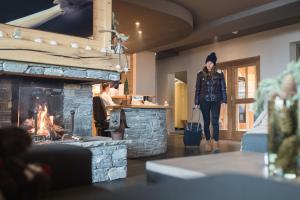 a woman walking with a suitcase in front of a fireplace at CGH Résidences & Spas les Chalets du Soleil Contemporain in Les Menuires +31 photos