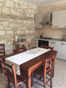 cocina con mesa de madera con sillas y cocina con electrodomésticos blancos en Pezzelelle en Roccamorice