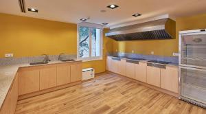 a large kitchen with yellow walls and wooden floors at Alberg Abat Oliba in Montserrat