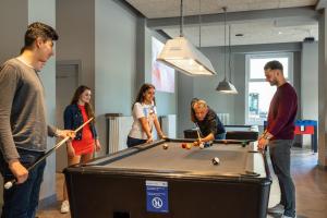 a group of people standing around a pool table at a&o Hamburg City in Hamburg