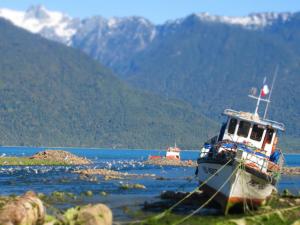 a boat sitting on the shore of a body of water at Cabaña la Vega in Hornopiren +5 photos