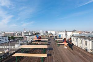 eine Gruppe von Menschen, die auf einem Deck auf einem Gebäude sitzen in der Unterkunft a&o Hamburg City in Hamburg