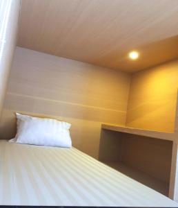 a bed with a white pillow in a room at XOXO Kuta Legian Hostel in Legian