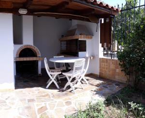 een patio met een tafel en stoelen en een oven bij Peggy's house in Monastiraki