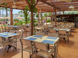 an empty restaurant with tables and chairs on a patio at BQ Alcudia Sun Village in Playa de Muro